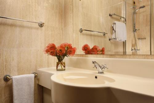 米兰UNAHOTELS Scandinavia Milano的浴室设有水槽和红花花瓶