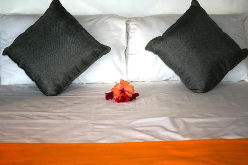 Kilwa MasokoKilwa Beach Lodge的一张带两个枕头的白色床和红色的花朵