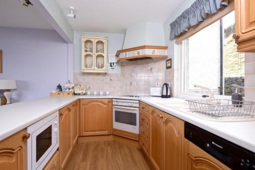 杰德堡Tweed Cottage的厨房配有木制橱柜、水槽和窗户。