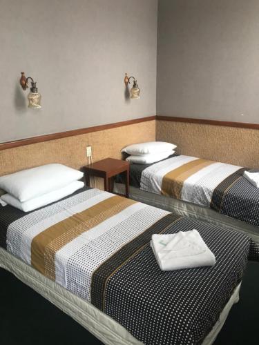 旺阿雷Grand Hotel - Whangarei的两张位于酒店客房的床,配有毛巾
