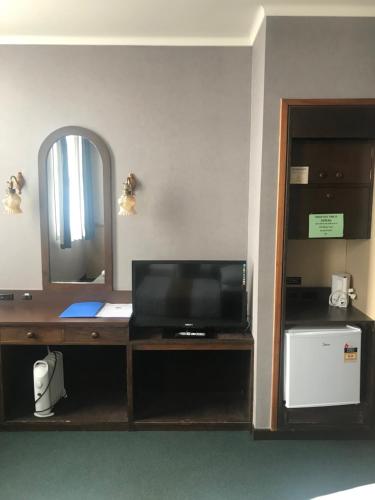 旺阿雷Grand Hotel - Whangarei的客房设有一张带电视和镜子的书桌
