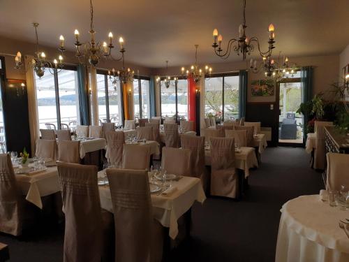 Peyrat-le-ChâteauHotel Restaurant La Caravelle的用餐室配有白色桌椅和吊灯。