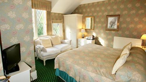 尚克林Rylstone Manor的一间卧室配有一张床、一把椅子和电视