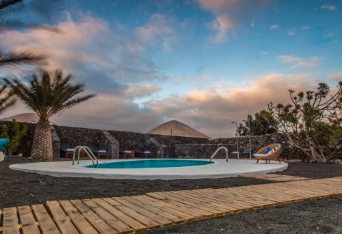 蒂亚斯Los Lirios Hotel Rural - Adults Only的一座棕榈树和金字塔背景的游泳池