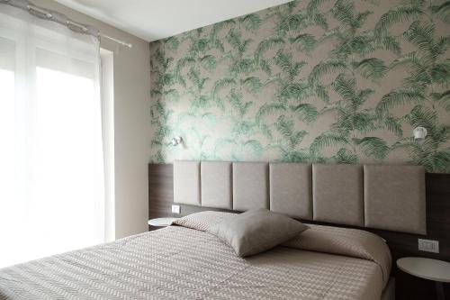 拉齐塞Menta e Rosmarino Rooms的一间卧室配有一张带热带壁纸的床