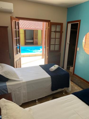 帕拉蒂Pousada Acquarela的一间卧室设有两张床,一扇通往游泳池的门