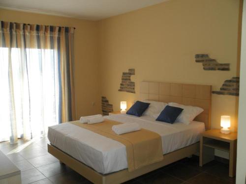 莫奈姆瓦夏卡萨莱别墅旅馆的卧室配有带蓝色枕头的大型白色床