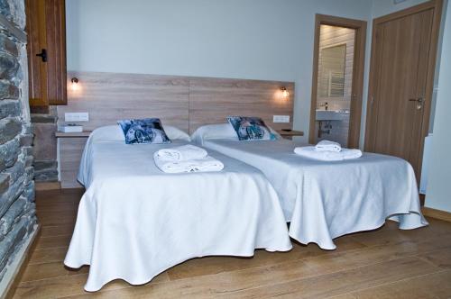 萨里亚PENSION SERRANO的配有2张床的客房内配有白色床单和毛巾