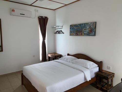 珍南海滩Hujung Kampung Estate的一间卧室配有一张带白色床单的床和一扇窗户。