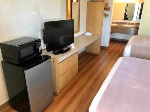 西塔科西雅图 - 塔科玛机场超值酒店的一间带一张床和电视的房间以及一间带一张高潮床的房间。