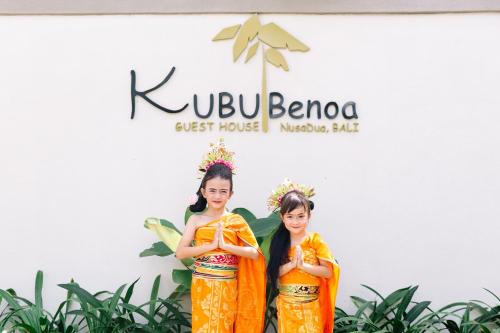 努沙杜瓦Kubu Benoa Guest House的两个穿着橙色制服的女孩站在标志牌前