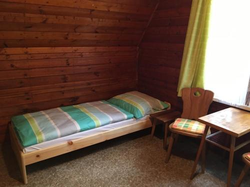 多克西Chata Pod Bílým kamenem的小木屋内的一张床位,配有桌子和椅子
