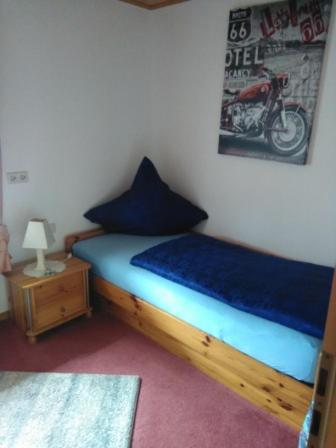 达森多夫Ferienwohnung Hops的卧室配有一张带蓝色床单的床和壁挂式摩托车。