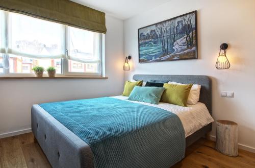 维尔纽斯Brand new modern townhouse的一间卧室配有一张带蓝色床单的床和两个窗户。