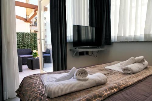 那不勒斯Le Corti del Re的客房内的一张带毛巾的床和一台电视
