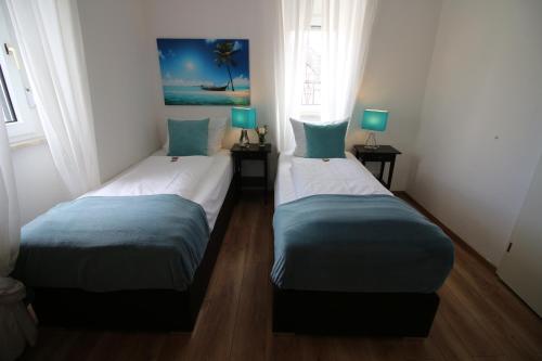 巴特萨尔奇利夫Apart Hotel Paradies的带2扇窗户的客房内的2张单人床