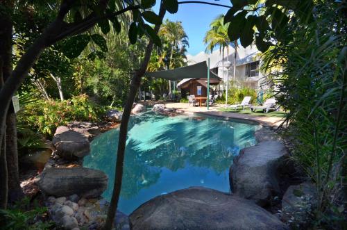 卡伦德拉Raintrees Moffat Beach的一座游泳池,位于一个拥有岩石和房子的庭院内