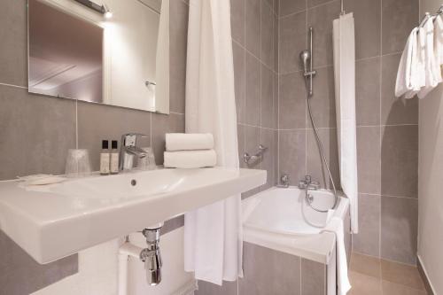巴黎圣罗奇酒店的白色的浴室设有水槽和卫生间。