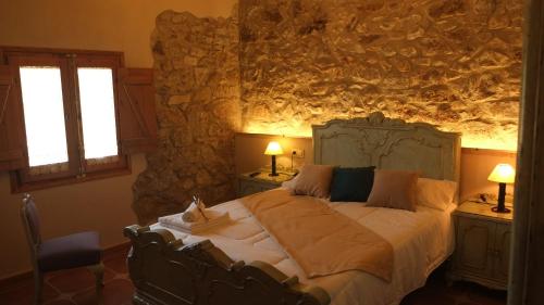 佩雷拉达La Masia de Montpedrós的卧室配有一张石墙内的大床