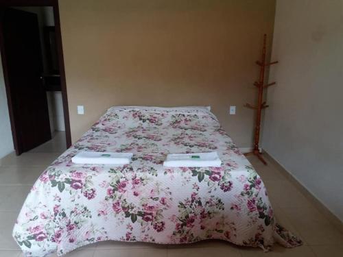 瓦尔任博尼塔Pousada Recanto do Sossego- Serra da Canastra的一间卧室配有一张带粉红色花卉床罩的床。