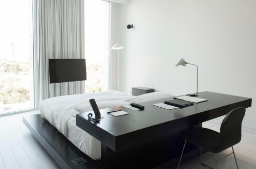 蒙特雷Habita Monterrey, a Member of Design Hotels的一间卧室配有一张桌子、一张床和一个窗户