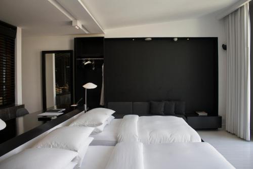 蒙特雷Habita Monterrey, a Member of Design Hotels的卧室配有白色的床和黑色的墙壁