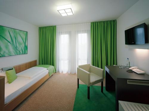 德累斯顿德累斯顿学院酒店的酒店客房配有一张床、一张书桌和绿色窗帘