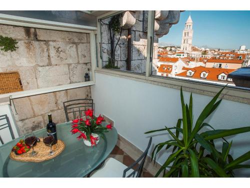 斯普利特Riva Royal Lounge Apartment的一张带鲜花和一瓶葡萄酒的桌子和一个窗口