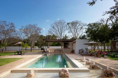 ConkalHotel Casa de Campo Conkal Merida的一个带凉亭的庭院内的游泳池