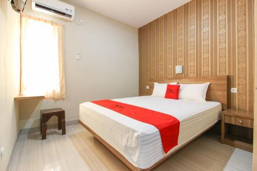 KalasanRedDoorz near Jogja Kembali Monument 3的一间卧室配有一张带红色毯子的大床