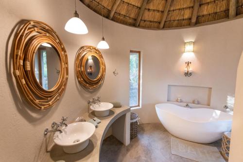 侯斯普瑞特Nyala Safari Lodge的浴室配有2个盥洗盆、浴缸和镜子