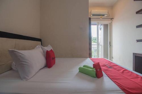 巴厘巴板RedDoorz near E Walk Mall Balikpapan的一张白色的床,上面有红色和绿色的枕头