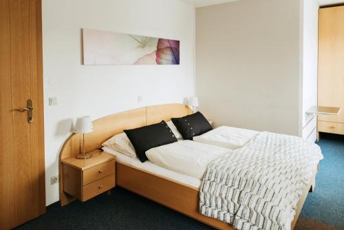 Feldkirchen bei GrazRestaurant Gästehaus Feldkirchen的一间卧室配有带白色床单和黑色枕头的床。