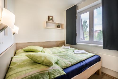 布达佩斯BpR Green Paradise Apartment的一间卧室配有一张带绿色枕头的床和一扇窗户
