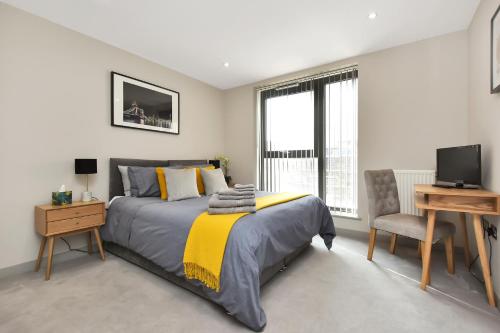 伦敦Esquire Apartments Ealing的一间卧室配有一张床、一张书桌和一台电视