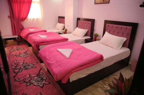开罗Queen Pyramids View Inn的配有粉红色床单的客房内的三张床
