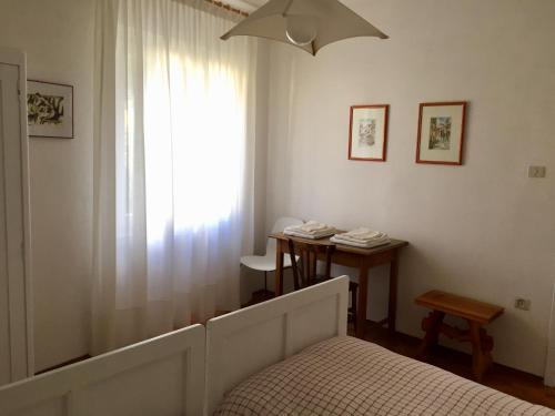 卡尔多纳佐Appartamento Balù的一间卧室配有一张床、一张桌子和一个窗户。