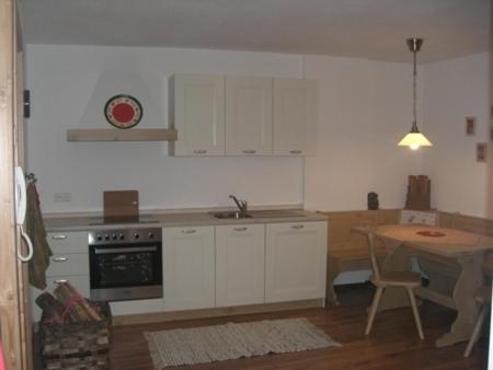 圣坎迪朵Haus Milli的厨房配有白色橱柜、桌子和水槽。
