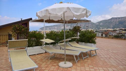 圣安吉洛弗拉维亚别墅酒店的庭院里摆放着一组椅子和一把遮阳伞