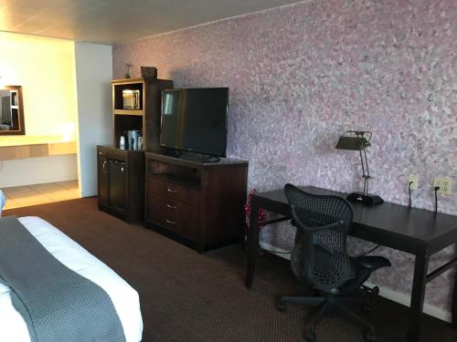 罗克斯普林Country West Motel of Rock Springs的酒店客房配有一张书桌、一台电视和一张床