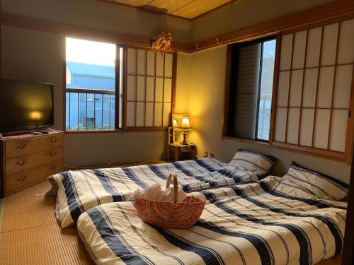 八千代市Koto House的一间卧室配有两张床,上面放着碗