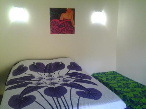 努库希瓦Fare Manutea的卧室配有一张床,墙上挂有绘画作品