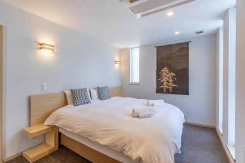 二世古Owl House Niseko的一间卧室配有一张带白色床单的大床