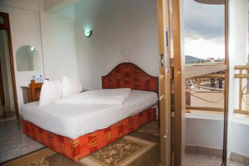 阿鲁沙纳特龙宫宾馆的一间卧室设有一张床和一个玻璃门