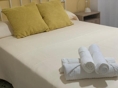 塞维利亚Amate con encanto的一张白色的床,上面有3条滚毛巾