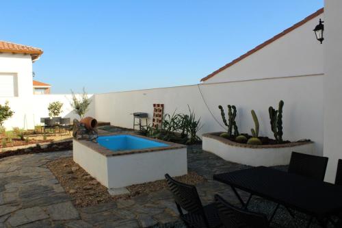 Casas de Don PedroCasa Rural El Nidal的庭院设有游泳池、桌子和椅子。