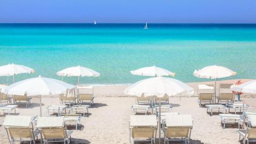 圣维托诺曼La Stratodda Dimora Loft Mare Bandiera Blu 2023的海滩上的一组椅子和遮阳伞