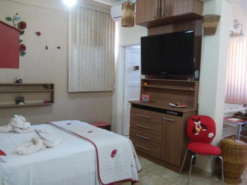 卡尚布Apart Hotel em Caxambu207的一间卧室配有一张床、一台电视和一张红色椅子