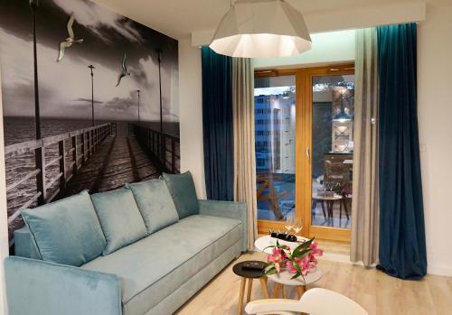 格丁尼亚Apartament Batorego 713的客厅配有蓝色的沙发和一幅码头画
