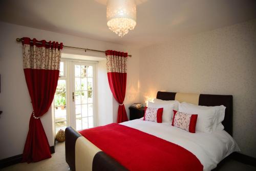 查希尔Birdsong Cottage Bed and Breakfast的一间卧室配有一张带红色窗帘的大床